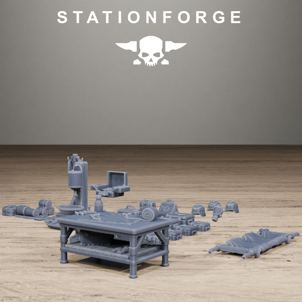 Grimguard Medical Bits terrain pieces arranged on a tabletop, including a med table, stretcher, packs, helmets, and medical supplies.