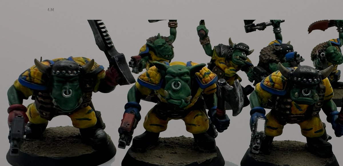 Close-up of hand-painted Guttertech Orc Raiders in yellow and blue armor with metal weapons and textured bases.
