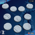 Round 3D‑printed scenic terrain bases with sci‑fi patterns including panels, treads, pipes, and hex textures